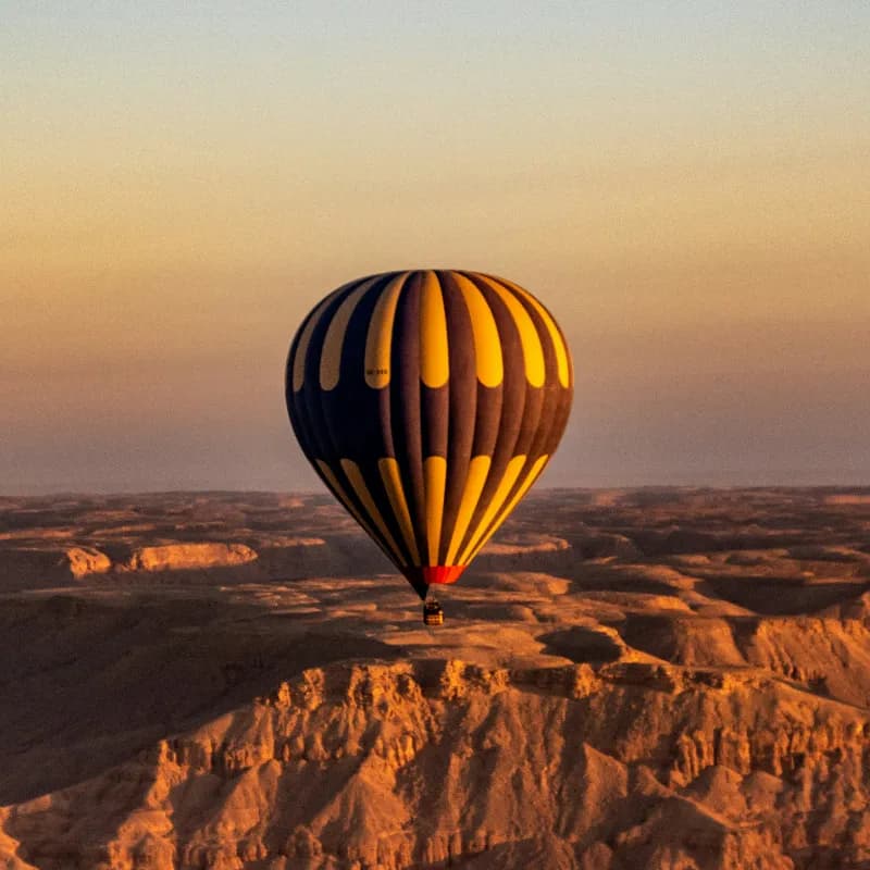 Hot air balloon over Luxor with Nile cruise ship below