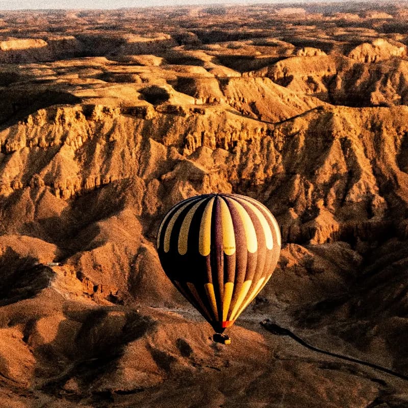 Hot air balloon over Luxor with ancient temples below
